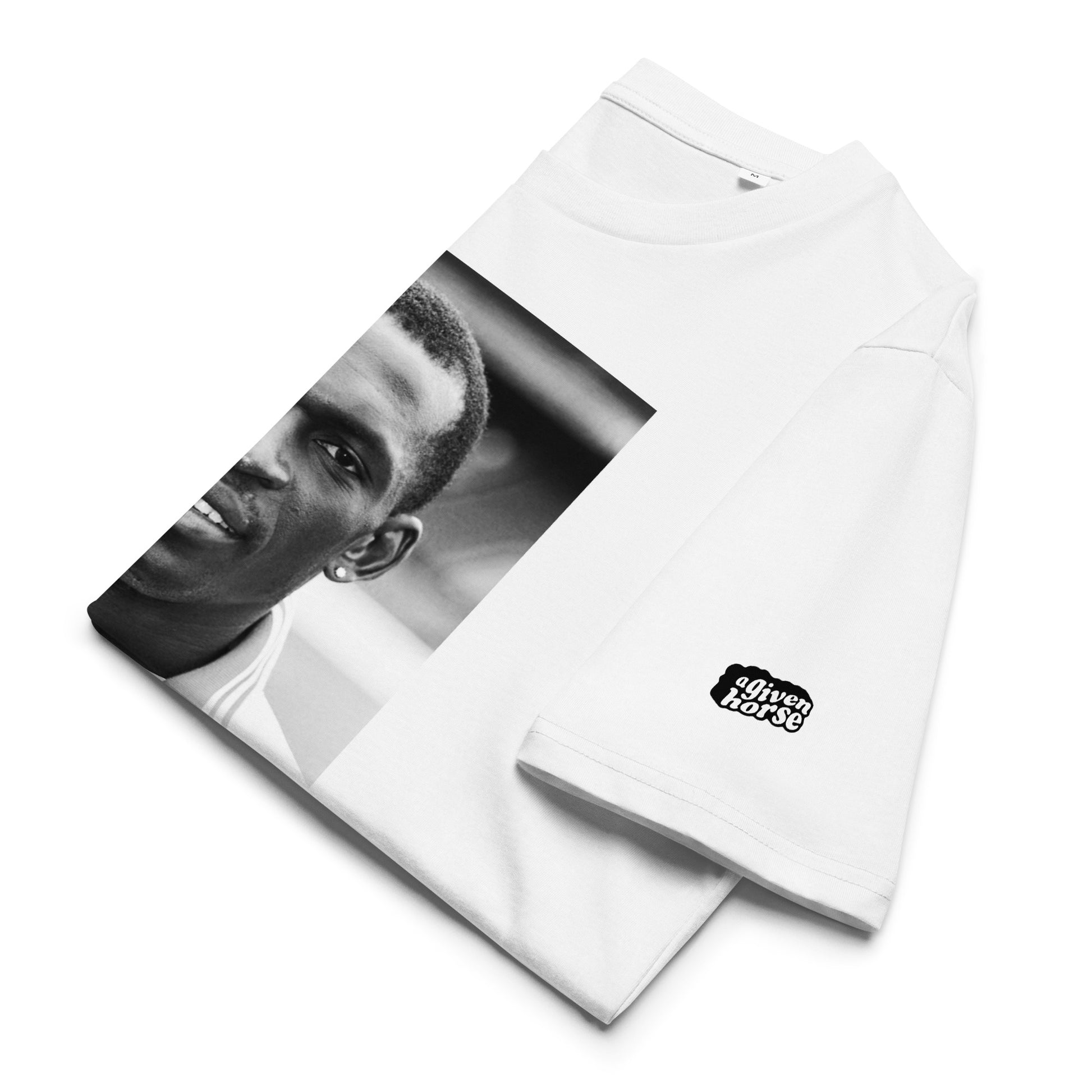 Wit T-Shirt met een afbeelding van Michael Obiku, ontwerp door De Zwarte Markt en verkrijgbaar bij cadeauwinkel 'A Given Horse'. Gevouwen.